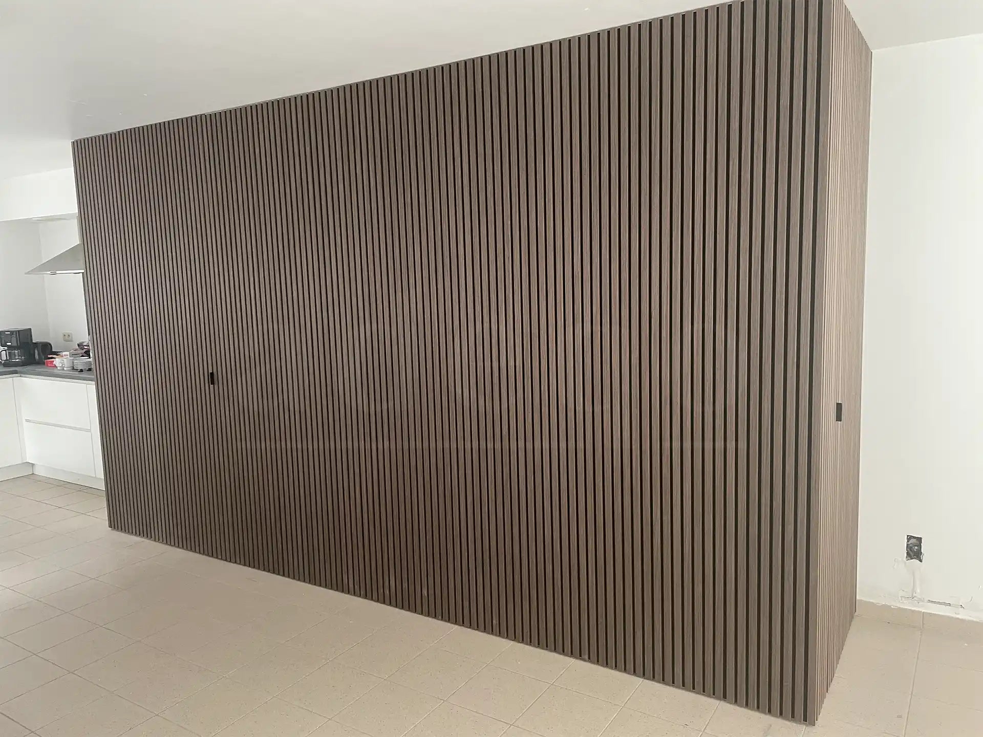 Moderne scheidingswand bekleed met Adeqo akoestische wandpanelen in Donker Walnoot, gelegen tussen keuken en woonruimte.