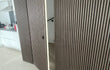 Verborgen deur naar trapopgang, bekleed met Adeqo akoestische wandpanelen in Donker Walnoot, geïntegreerd in de wand naast de keuken.