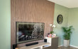 Woonkamer met tv-wand van Adeqo akoestisch wandpaneel in walnoot, gecombineerd met groene muur.