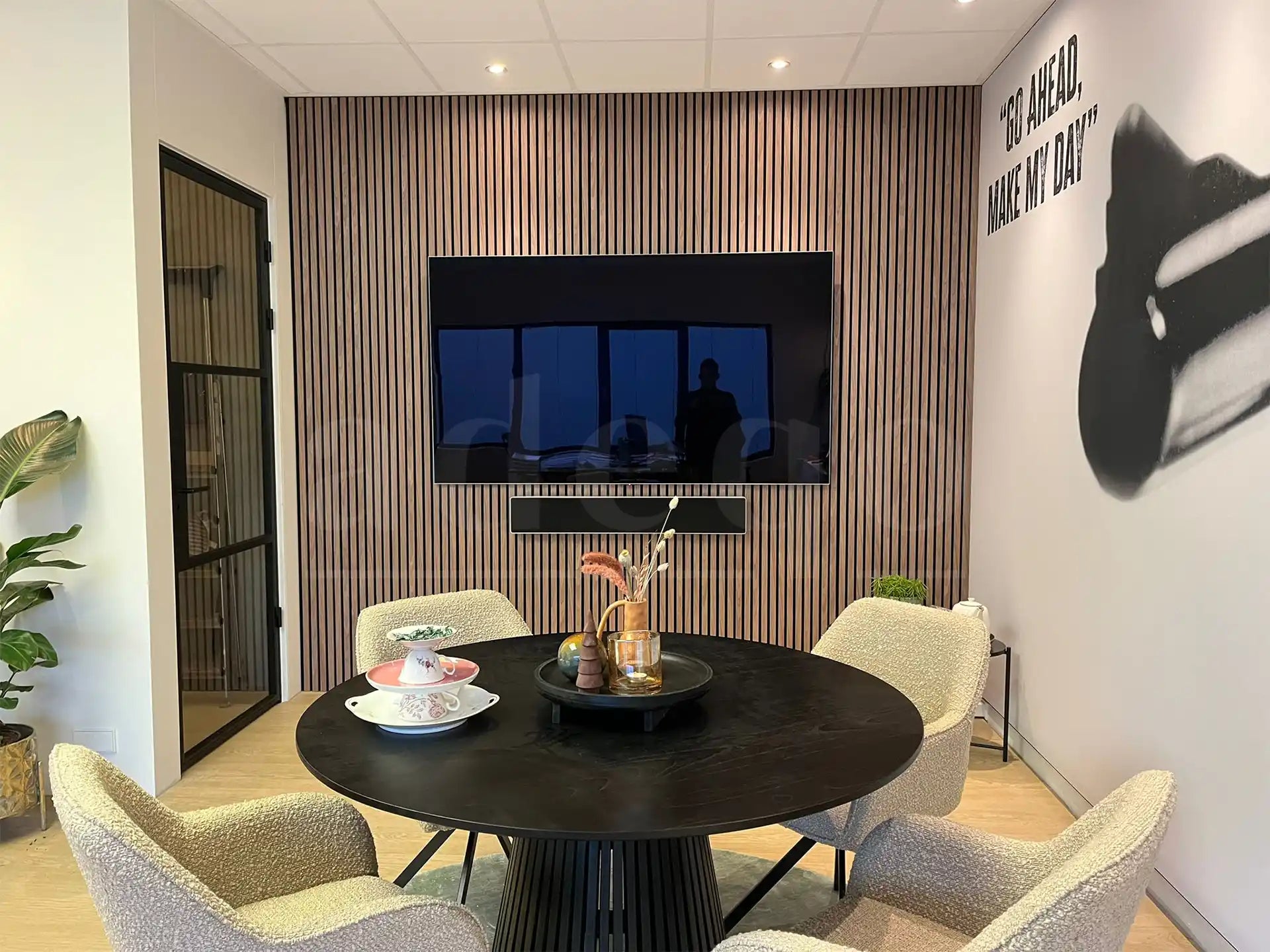 Moderne vergaderruimte met Adeqo akoestisch wandpaneel in Licht Walnoot, ronde tafel en luxe stoelen.