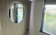 Kamer met ronde spiegel en Adeqo akoestisch wandpaneel in Natuurlijk Eiken voor een moderne uitstraling.