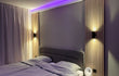 Slaapkamer met Adeqo akoestisch wandpaneel in Natuurlijk Eiken, sfeerverlichting en modern bed.