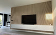 Moderne woonkamer met tv-wand van Adeqo akoestisch wandpaneel in Natuurlijk Eiken en wit zwevend tv-meubel.