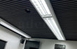 Akoestische wandpanelen in Zwart Eiken toegepast als plafondbekleding in een moderne kantoorruimte met geïntegreerde LED-verlichting en strakke afwerking.