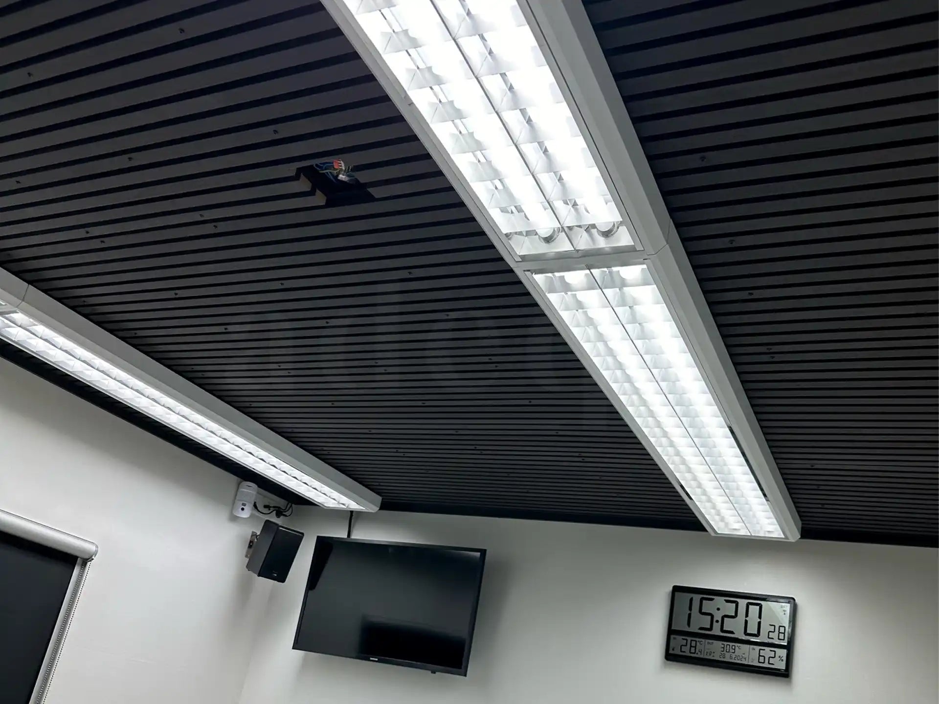 Akoestische wandpanelen in Zwart Eiken toegepast als plafondbekleding in een moderne kantoorruimte met geïntegreerde LED-verlichting en strakke afwerking.