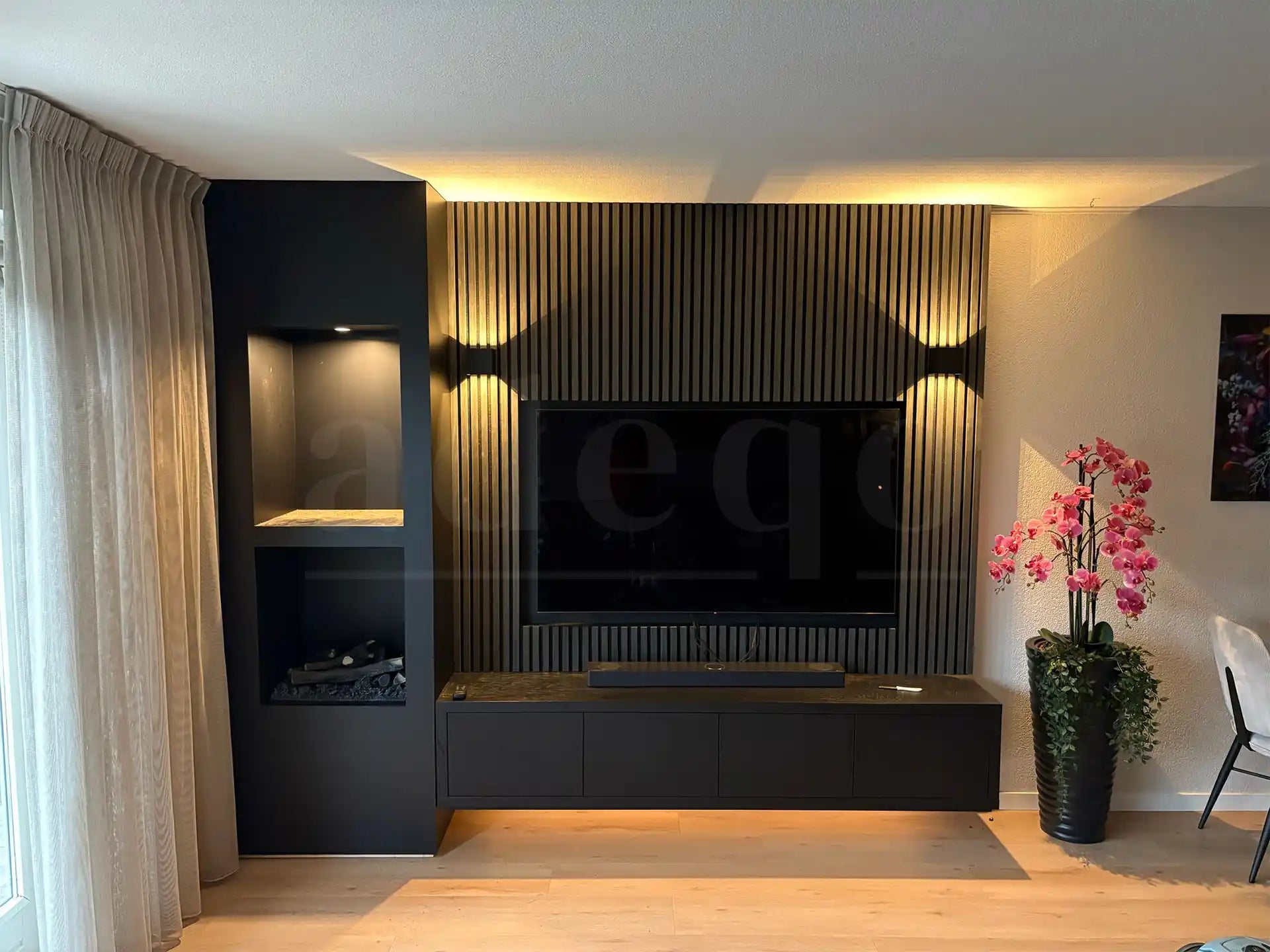 Moderne woonkamer met Zwarte Eiken akoestische wandpanelen van Adeqo als tv-wand, met ingebouwde verlichting en strakke zwarte meubels