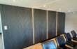 Akoestische wandpanelen in Zwart Eiken met verticale LED-strips, geplaatst in een moderne vergaderruimte voor optimale geluidsdemping en een luxe uitstraling.