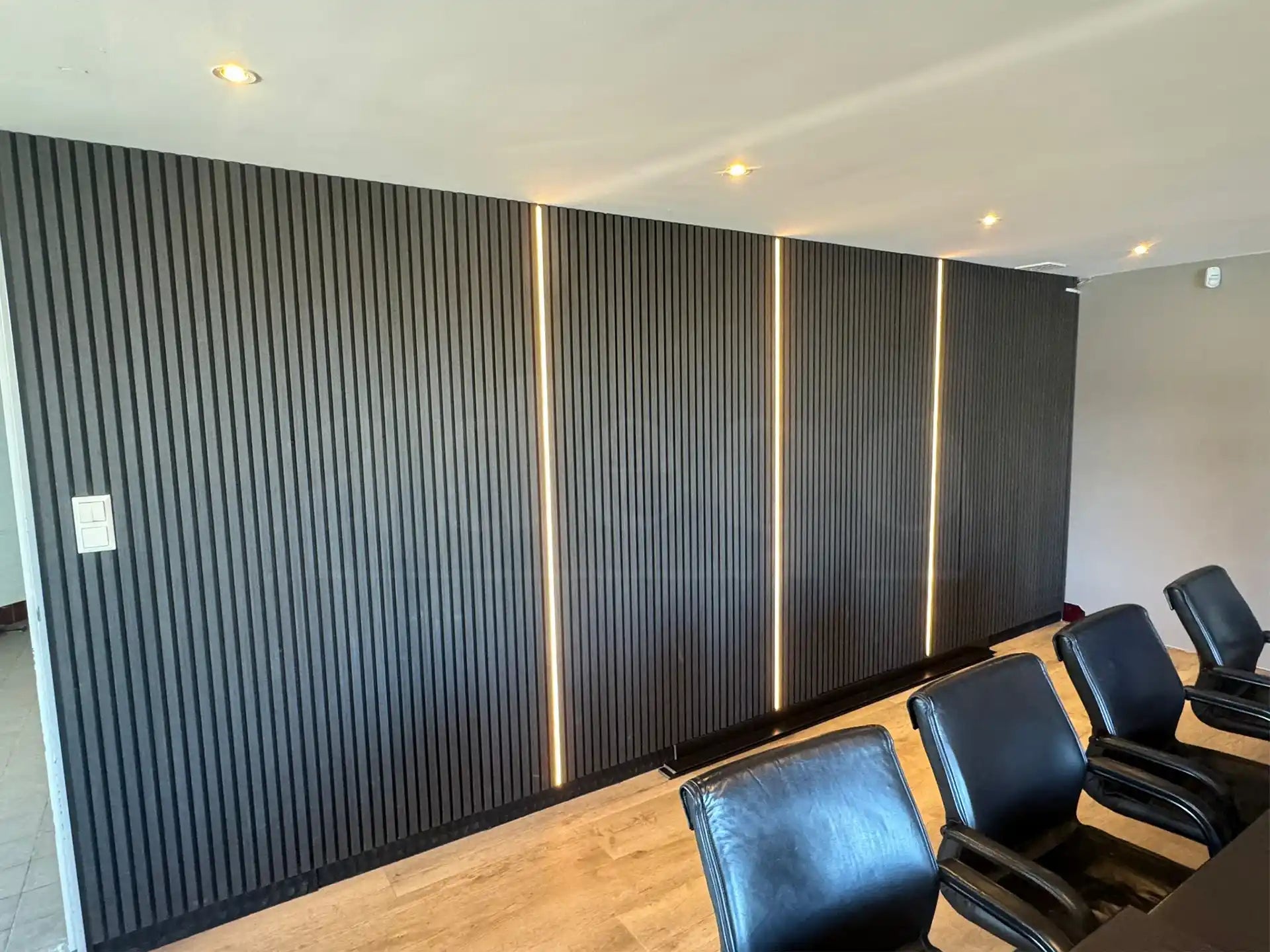 Akoestische wandpanelen in Zwart Eiken met verticale LED-strips, geplaatst in een moderne vergaderruimte voor optimale geluidsdemping en een luxe uitstraling.