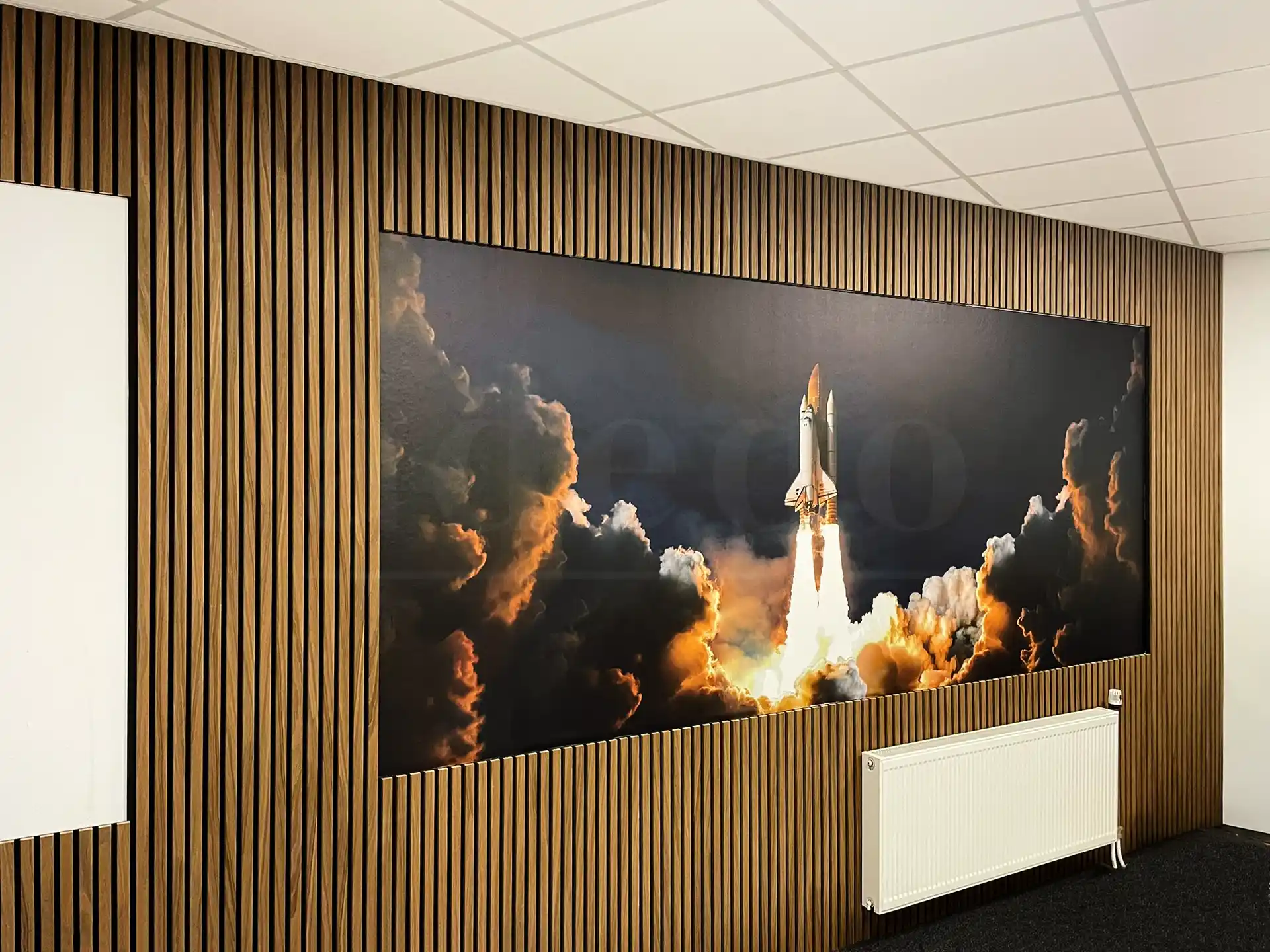 Kantoorruimte met Bruin Eiken akoestische wandpanelen van Adeqo, rondom een grote muurschildering van een raketlancering, voor een moderne en inspirerende uitstraling.