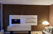 Woonkamer met Bruin Eiken akoestische wandpanelen van Adeqo als stijlvolle tv-wand, gecombineerd met wit zwevend meubel en moderne verlichting.
