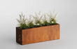 Cortenstalen plantenbak van 100x30x35 cm, gevuld met decoratief wit siergras tegen een neutrale achtergrond.