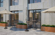 Sfeervol terras met Adeqo cortenstaal plantenbak 150x50x50 cm gevuld met groene beplanting, geplaatst langs een gevel met terrastafels en parasols.