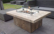 Adeqo Steigerhout Vuurtafel Verona in rechthoekige uitvoering, gemaakt van robuust steigerhout met ingebouwde rechthoekige brander en glasombouw, geplaatst op een terras met loungeset.