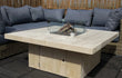 Adeqo Steigerhout Vuurtafel Verona in vierkante uitvoering, gemaakt van licht steigerhout met ingebouwde brander en glasombouw, geplaatst op een terras met loungeset.