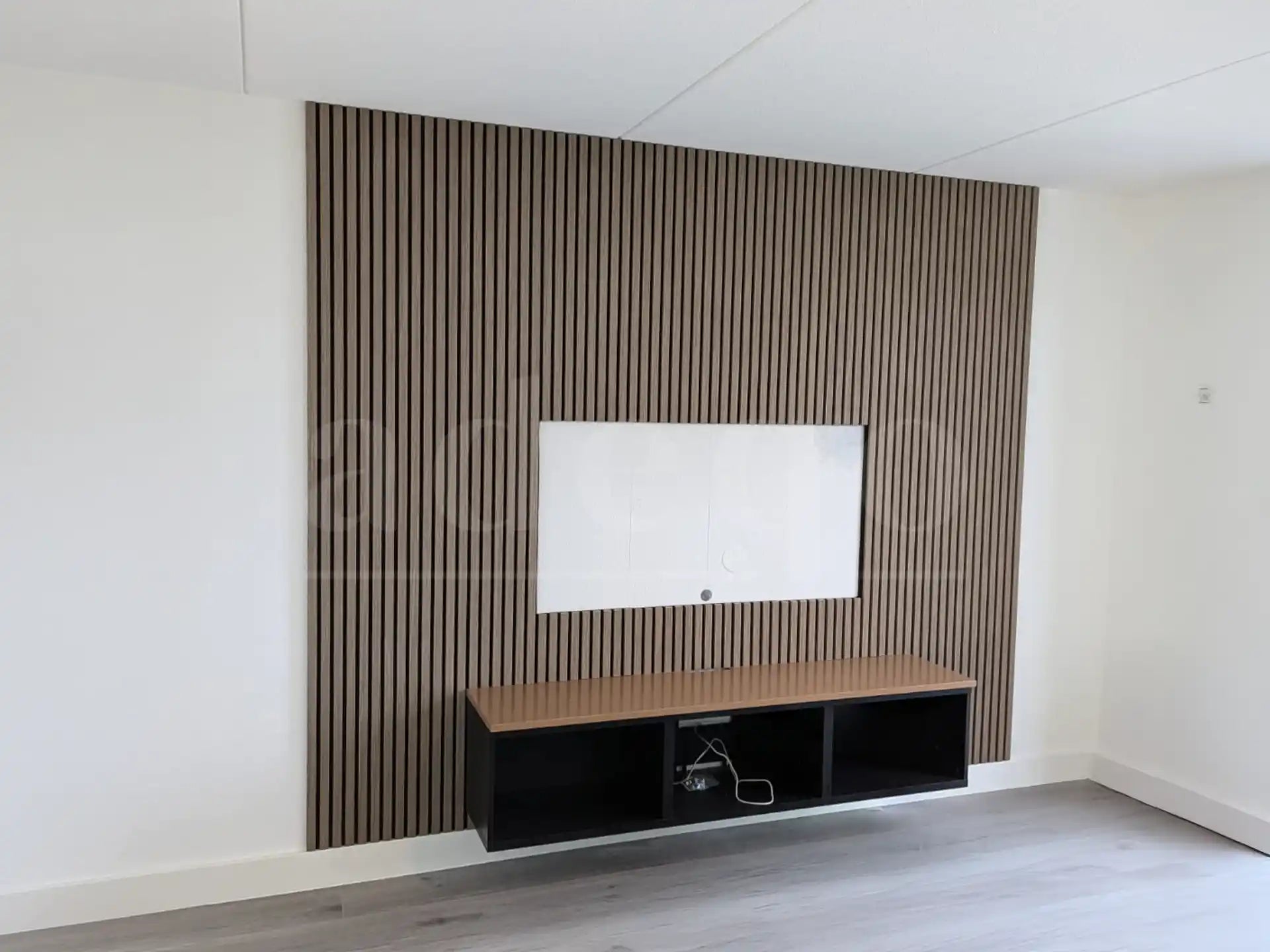 Moderne tv-wand met Adeqo akoestische wandpanelen in Verouderd Eiken, voorzien van een ingebouwde uitsparing voor een scherm en een minimalistisch tv-meubel.