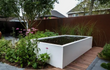 Adezz aluminium vijver geïntegreerd in een bloementuin, rechthoekig design met helder water, luxe tuininrichting.