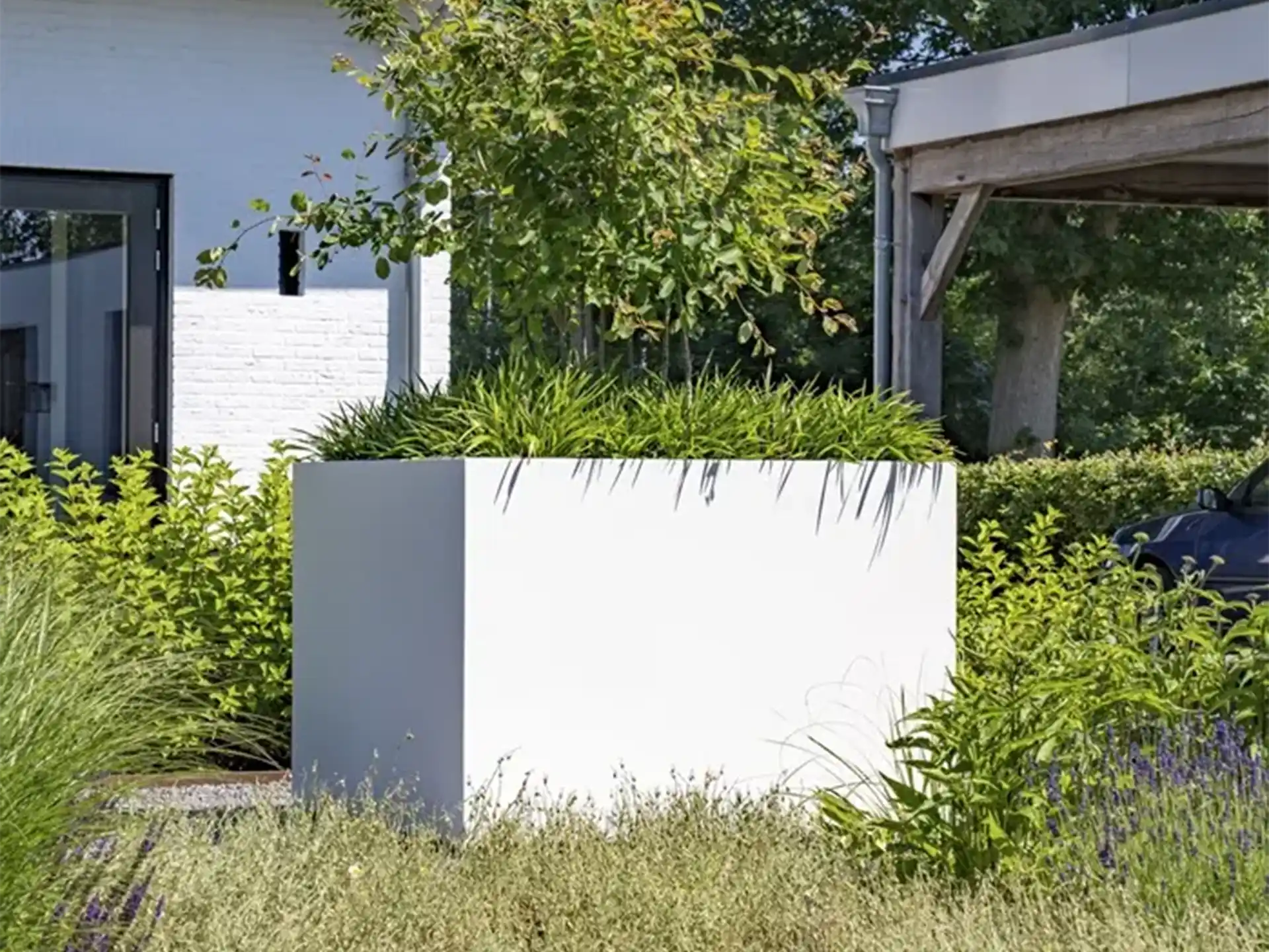 Grote witte Adezz Carrez aluminium plantenbak met wielen in een groene tuinomgeving.
