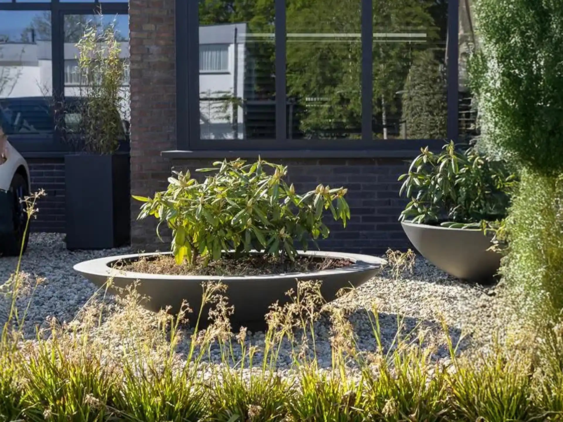 Adezz Ceder polyester plantenbak rond schaalmodel met groene planten en sierlijke uitstraling in de tuin.