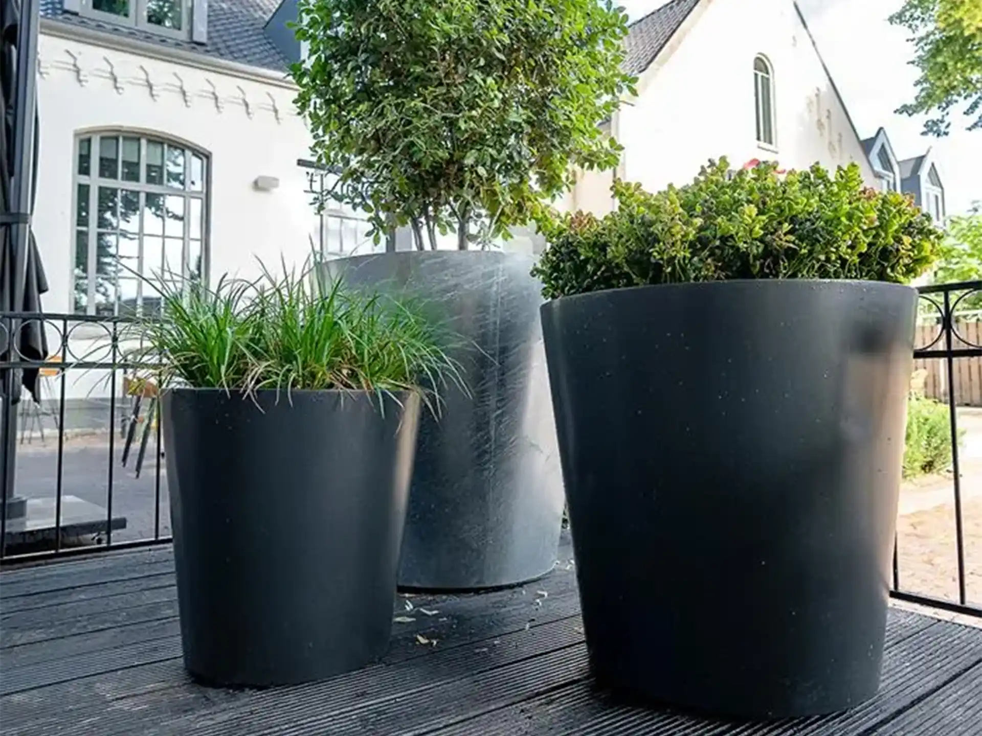 Set van Adezz Conic aluminium plantenbakken rond met verschillende hoogtes en beplanting in een moderne tuin.