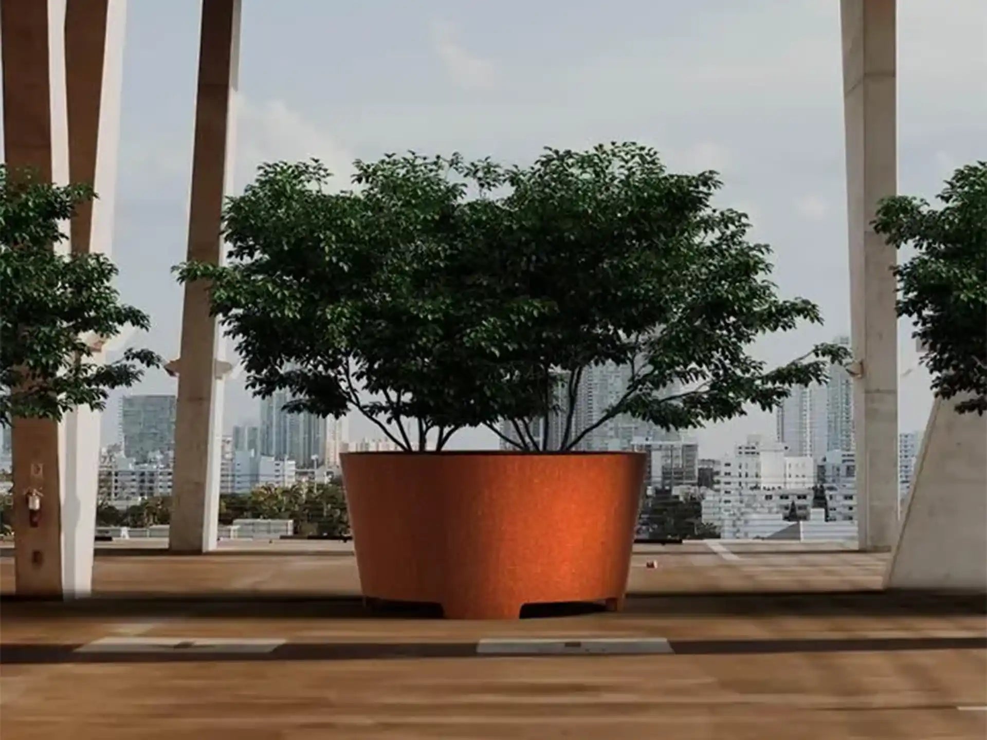 Grote Adezz Conic Cortenstaal Plantenbak Rond met poten en bodem, beplant met een boom op een modern terras met stadszicht.