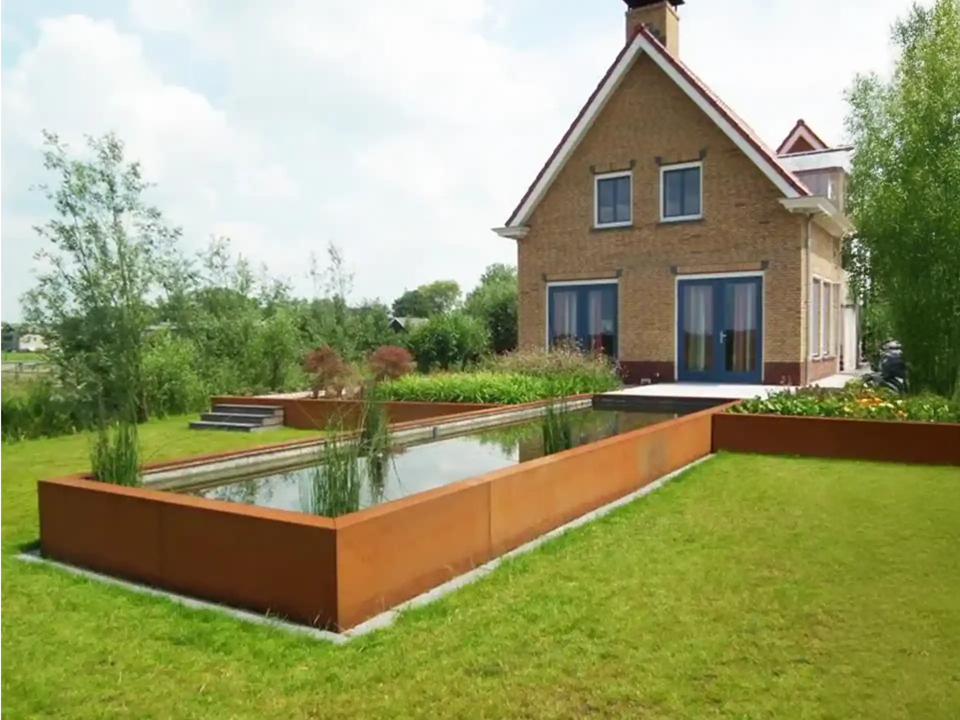 Adezz vijver van cortenstaal, groot rechthoekig model geplaatst in een landelijke tuin, zorgt voor rust en sfeer.