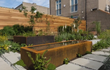 Adezz vijver van cortenstaal in een moderne tuin, rechthoekig design met waterplanten en strakke bestrating.