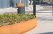 Adezz Ellipse Cortenstaal Plantenbak Ovaal met bodem, beplant met lage groene planten op een modern stadsplein.