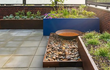 Adezz kantopsluiting van gezet cortenstaal toegepast langs een terras met beplanting en grind voor een moderne uitstraling.