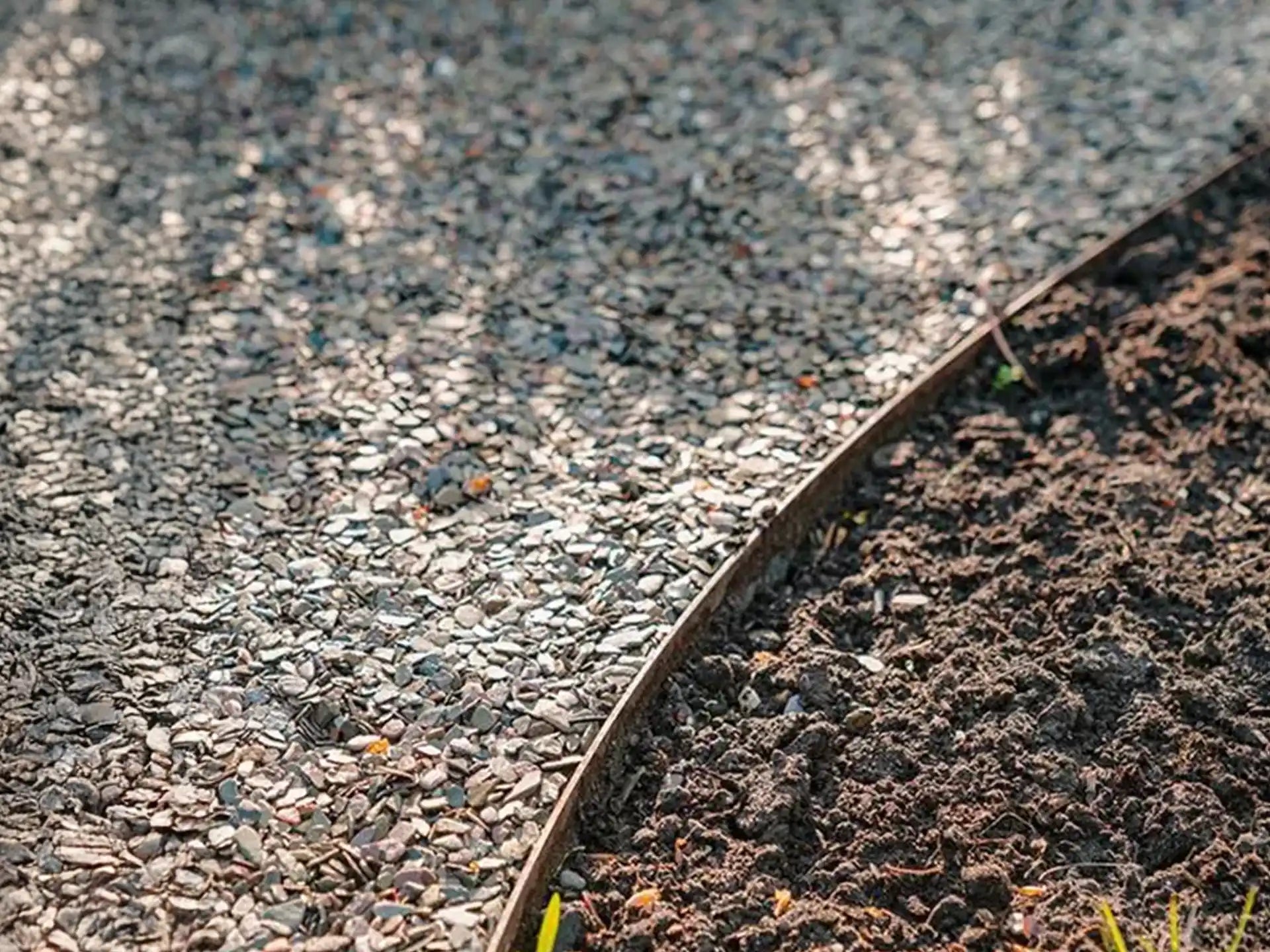 Adezz kantopsluiting cortenstaal toegepast langs een grindpad en aarde, voor strakke en duurzame afwerking in de tuin.