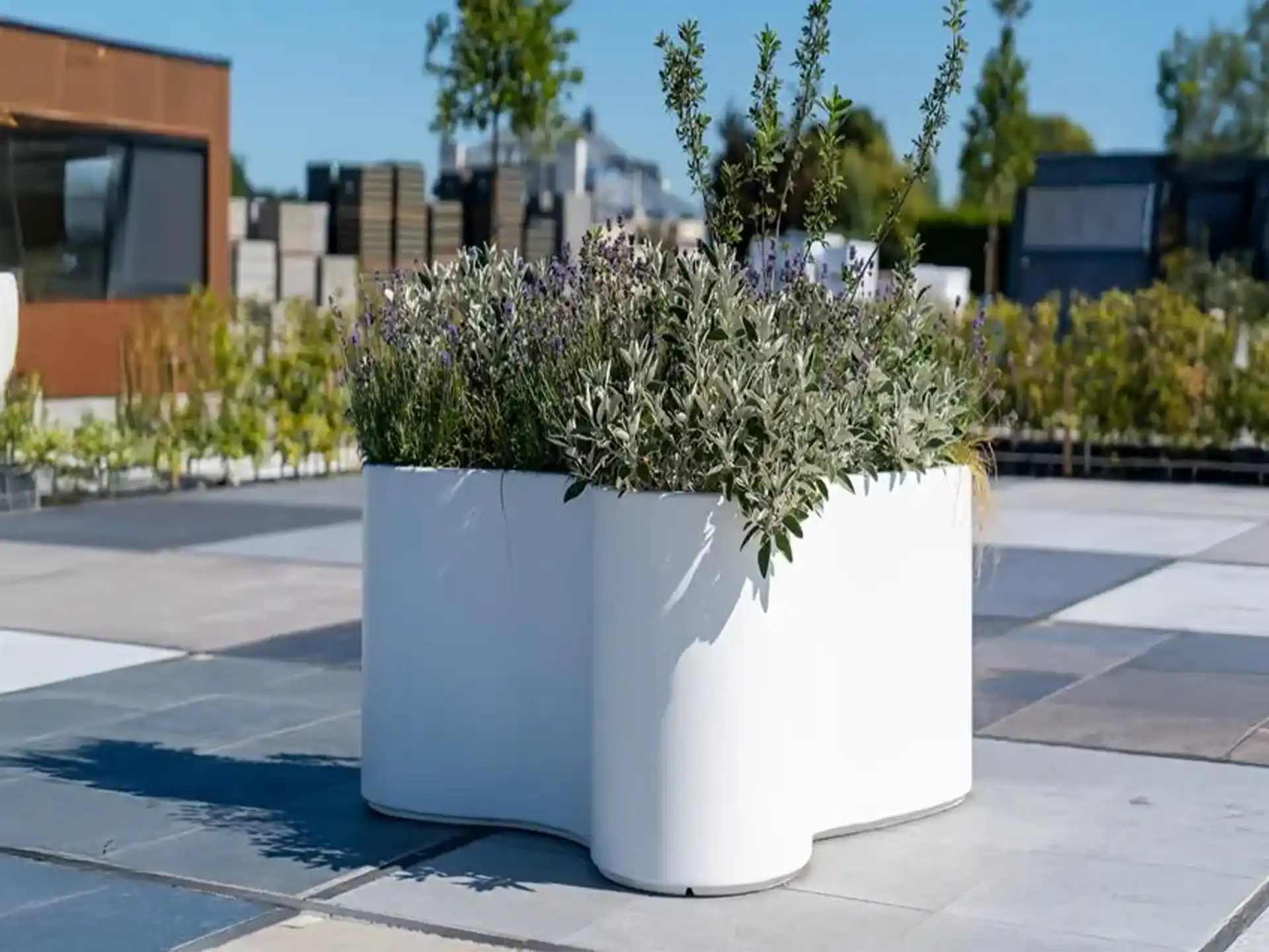 Adezz Organ polyester plantenbak rond organisch model in wit met grijze tegels op een dakterras.