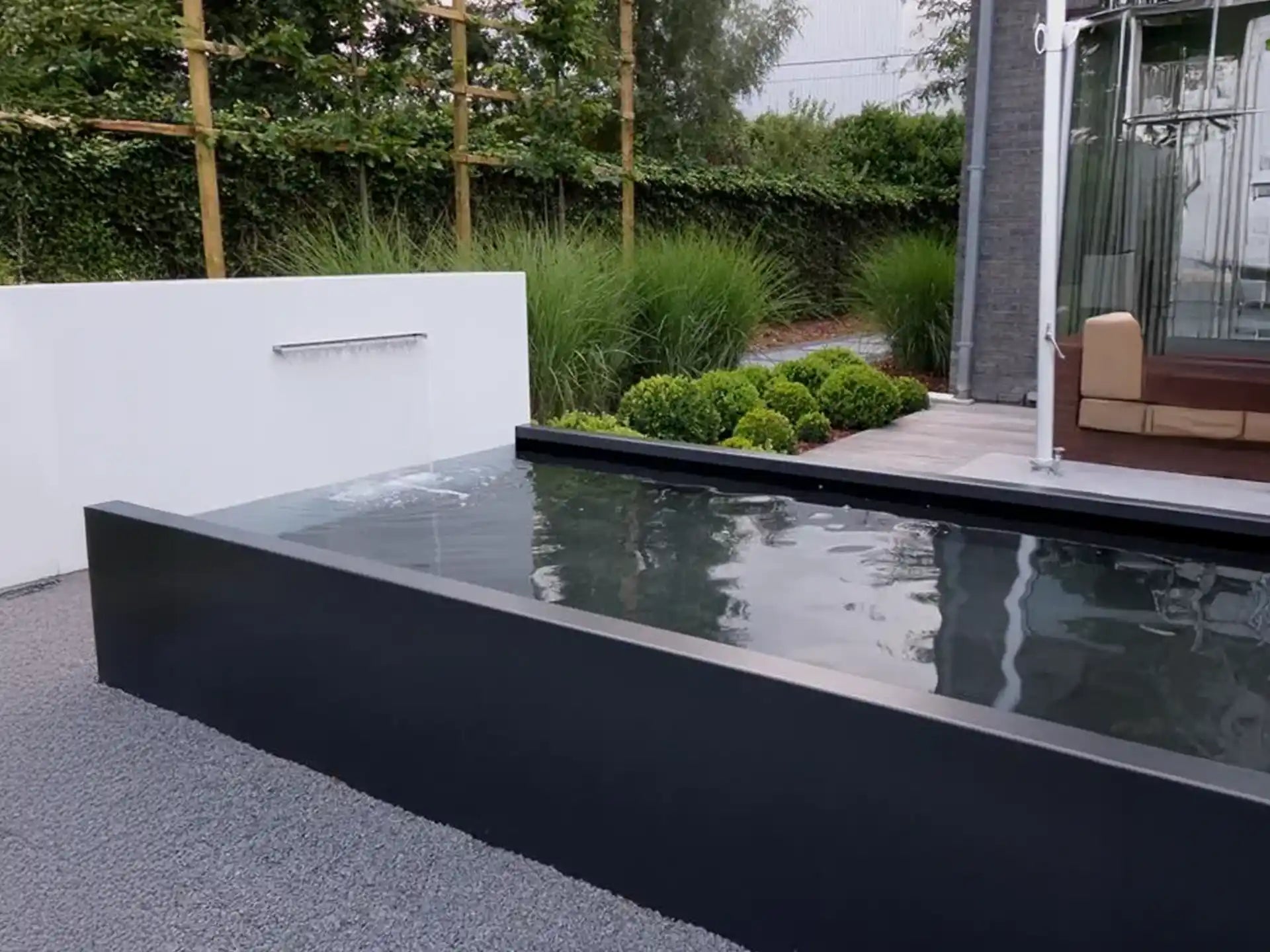 Adezz vijvermuur op aluminium vijver, moderne tuinopstelling met geïntegreerde waterval en pomp.