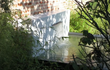 Adezz vijvermuur gemonteerd op aluminium vijver, waterornament met brede waterval, sfeervol in een groene tuin.