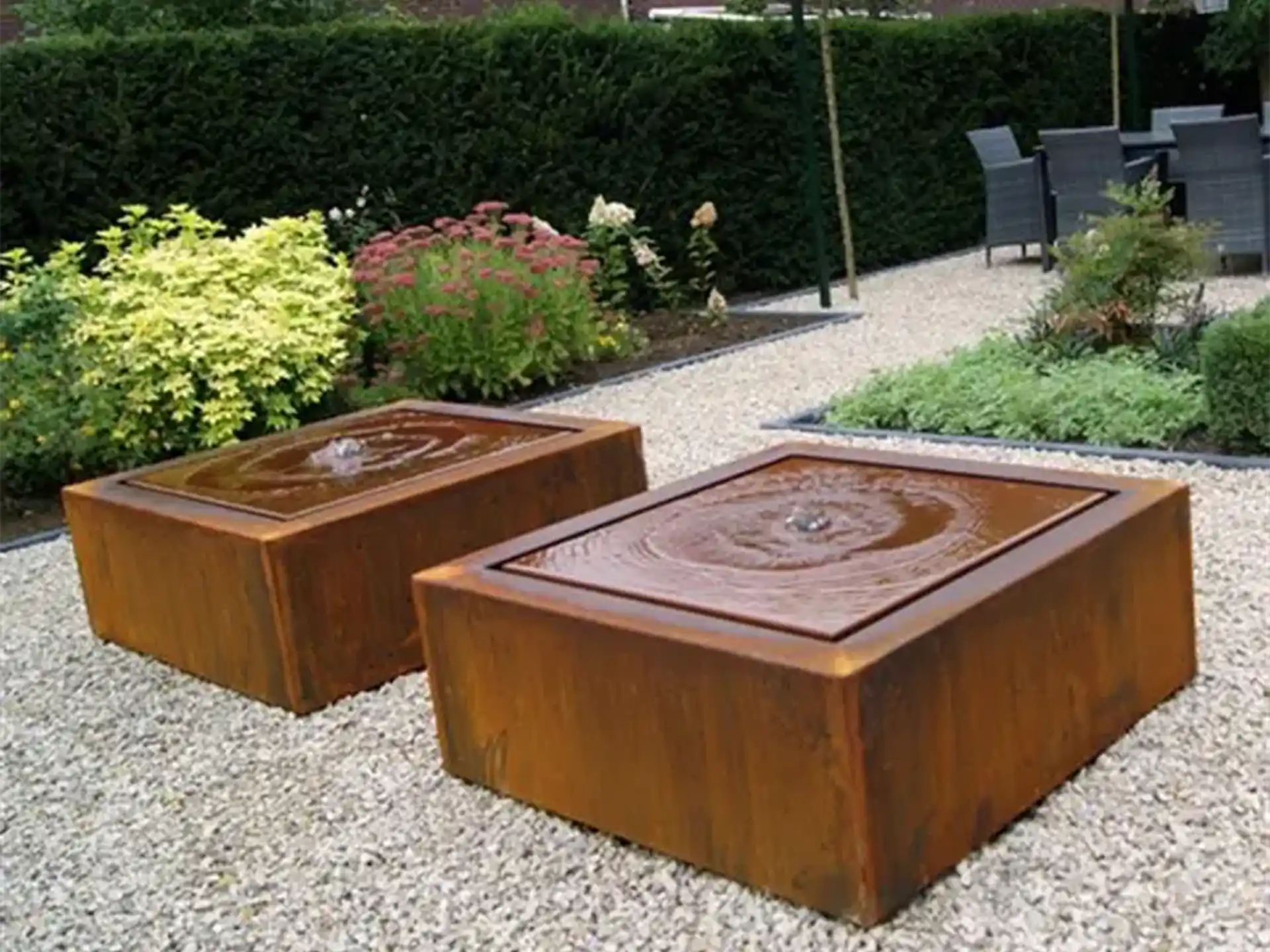 Twee vierkante Adezz watertafels van cortenstaal met fontein, stijlvol opgesteld in een moderne tuin.
