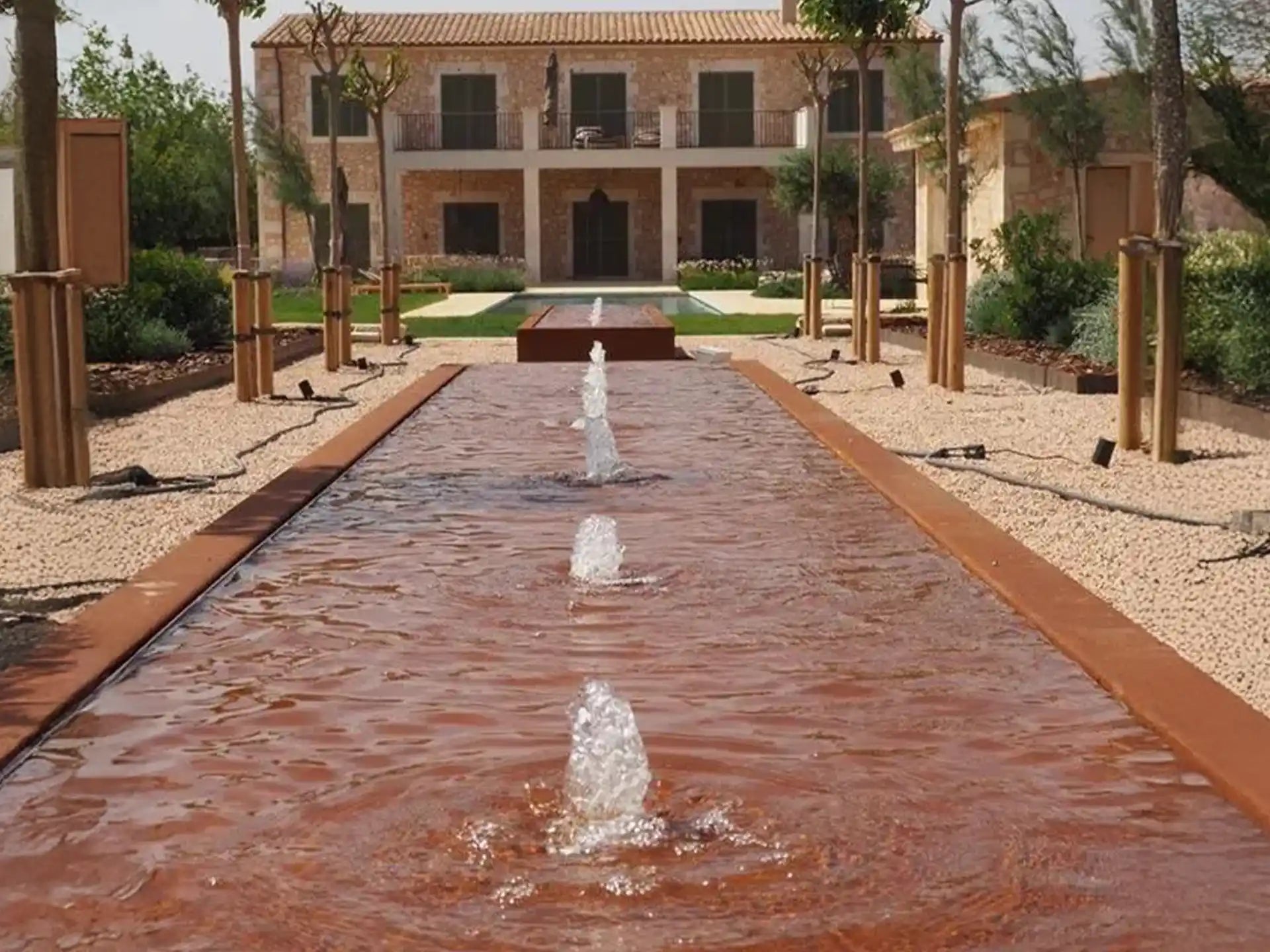 Lange rij Adezz cortenstaal watertafels met fonteinen, toegepast in een luxe tuinproject met strak ontwerp.