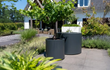 Een Adezz ronde aluminium watertafel met fontein in een ruime tuin bij een moderne woning.