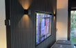 Moderne woonkamer met Zwart Eiken akoestische wandpanelen, ingebouwde tv en sfeervolle wandverlichting, uitgevoerd als akupanel akoestisch paneel.