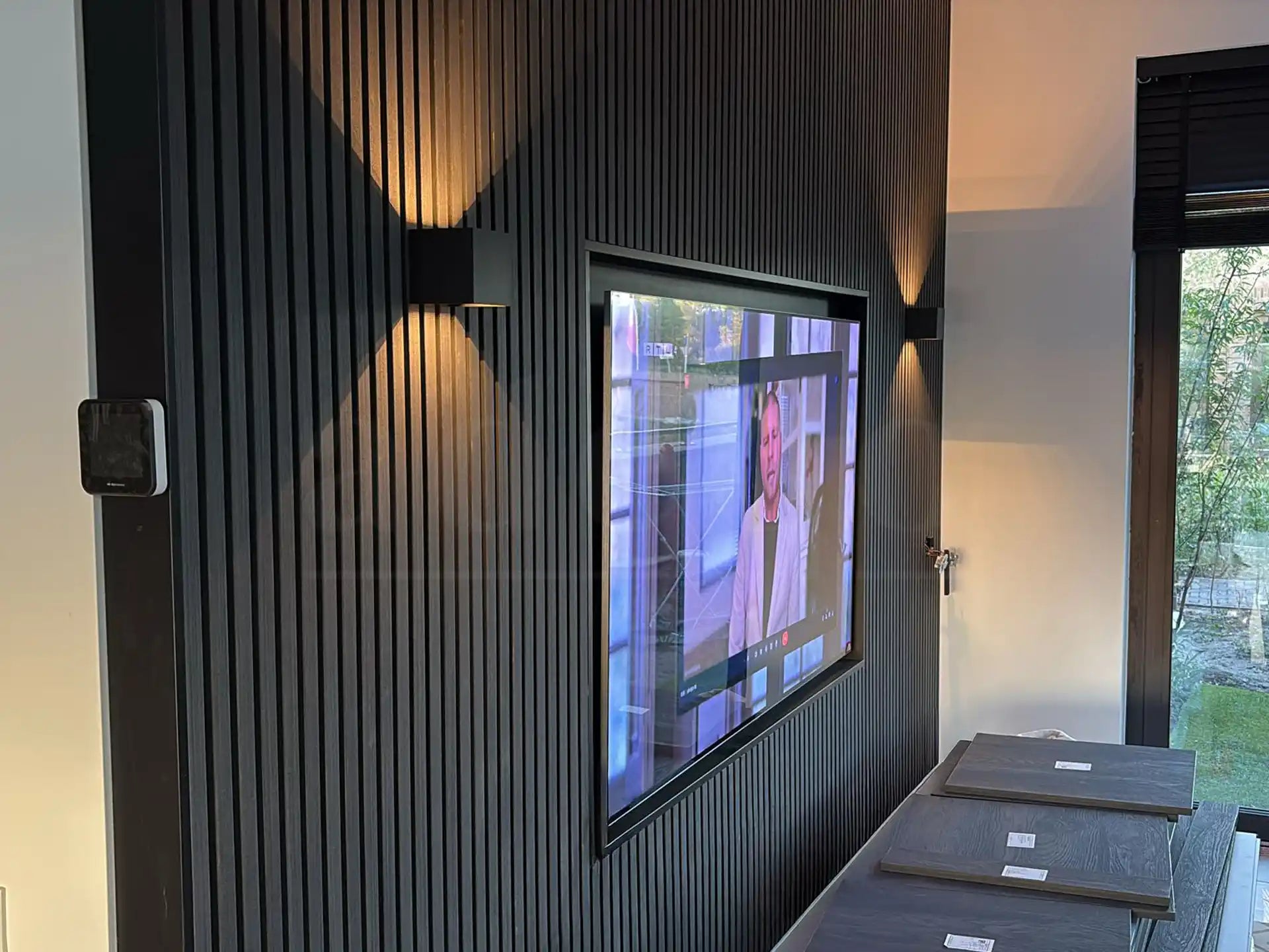 Moderne woonkamer met Zwart Eiken akoestische wandpanelen, ingebouwde tv en sfeervolle wandverlichting, uitgevoerd als akupanel akoestisch paneel.