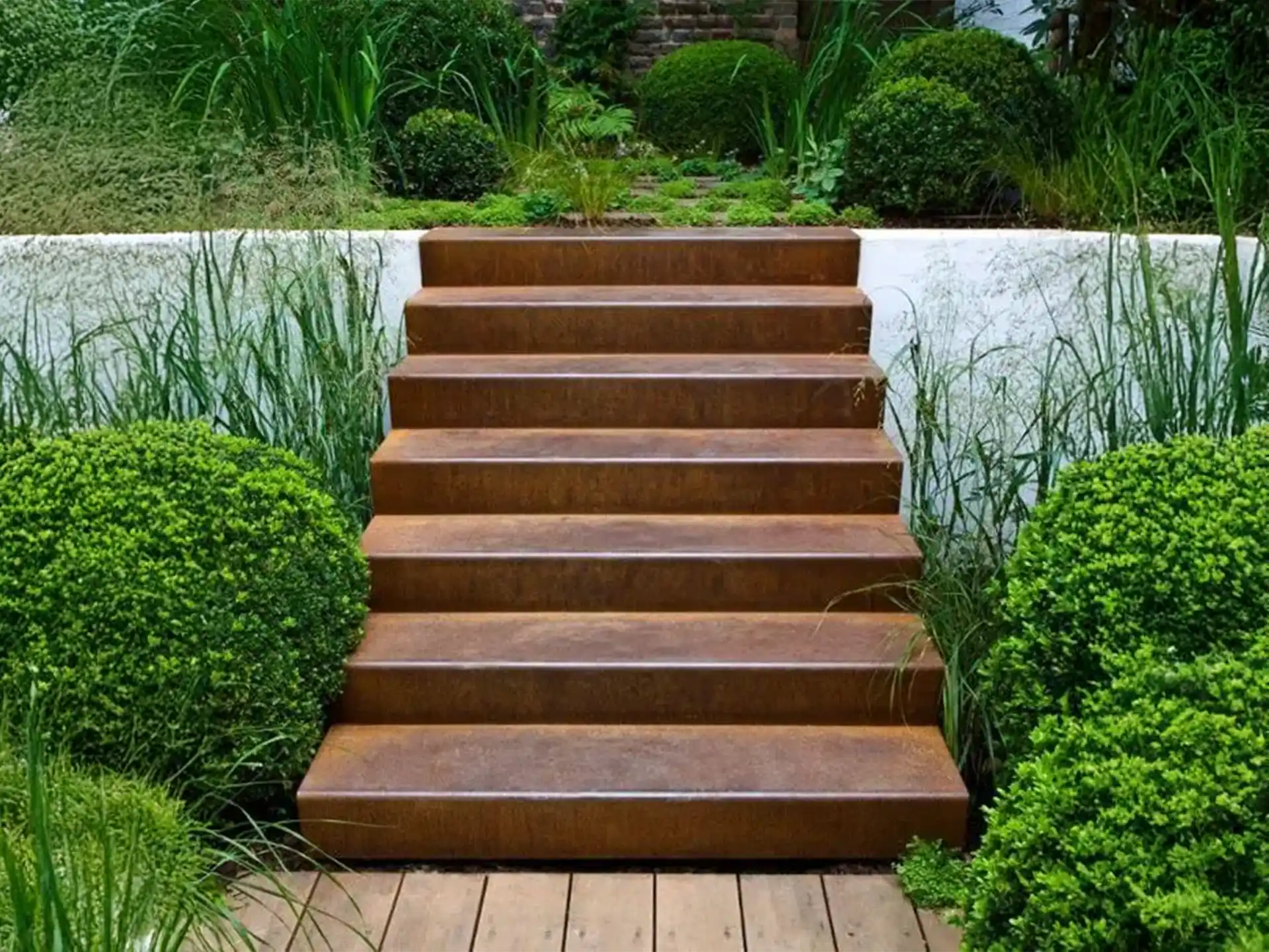 Strakke Adezz kant en klare trap van cortenstaal als tuintrap, omgeven door sierlijke groene beplanting in een luxe tuinontwerp.
