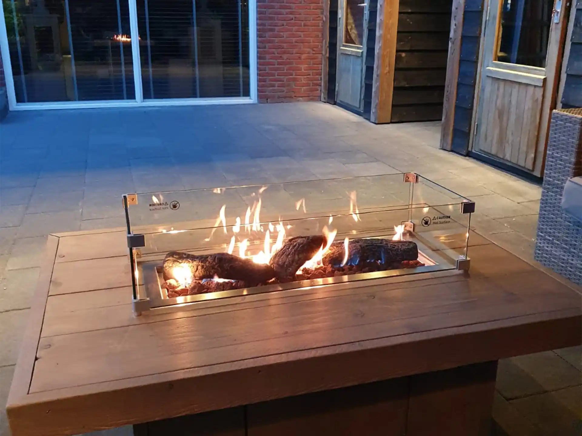 ofire glasombouw 61 × 33 cm in gebruik op een vuurtafel met brandende inbouwbrander, moderne setting.