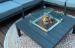 Gofire inbouwbrander 40 × 40 cm in moderne loungetafel met glasombouw, omringd door zitbanken op een buitenkleed.