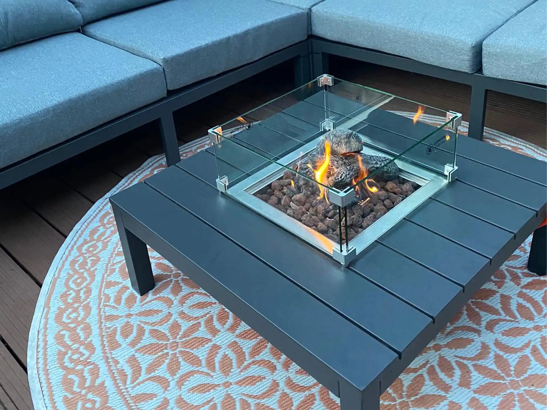 Gofire inbouwbrander 40 × 40 cm in moderne loungetafel met glasombouw, omringd door zitbanken op een buitenkleed.