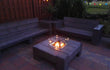 Gofire inbouwbrander 40 × 40 cm brandend in houten vuurtafel in een sfeervolle tuinsetting met buitenverlichting.