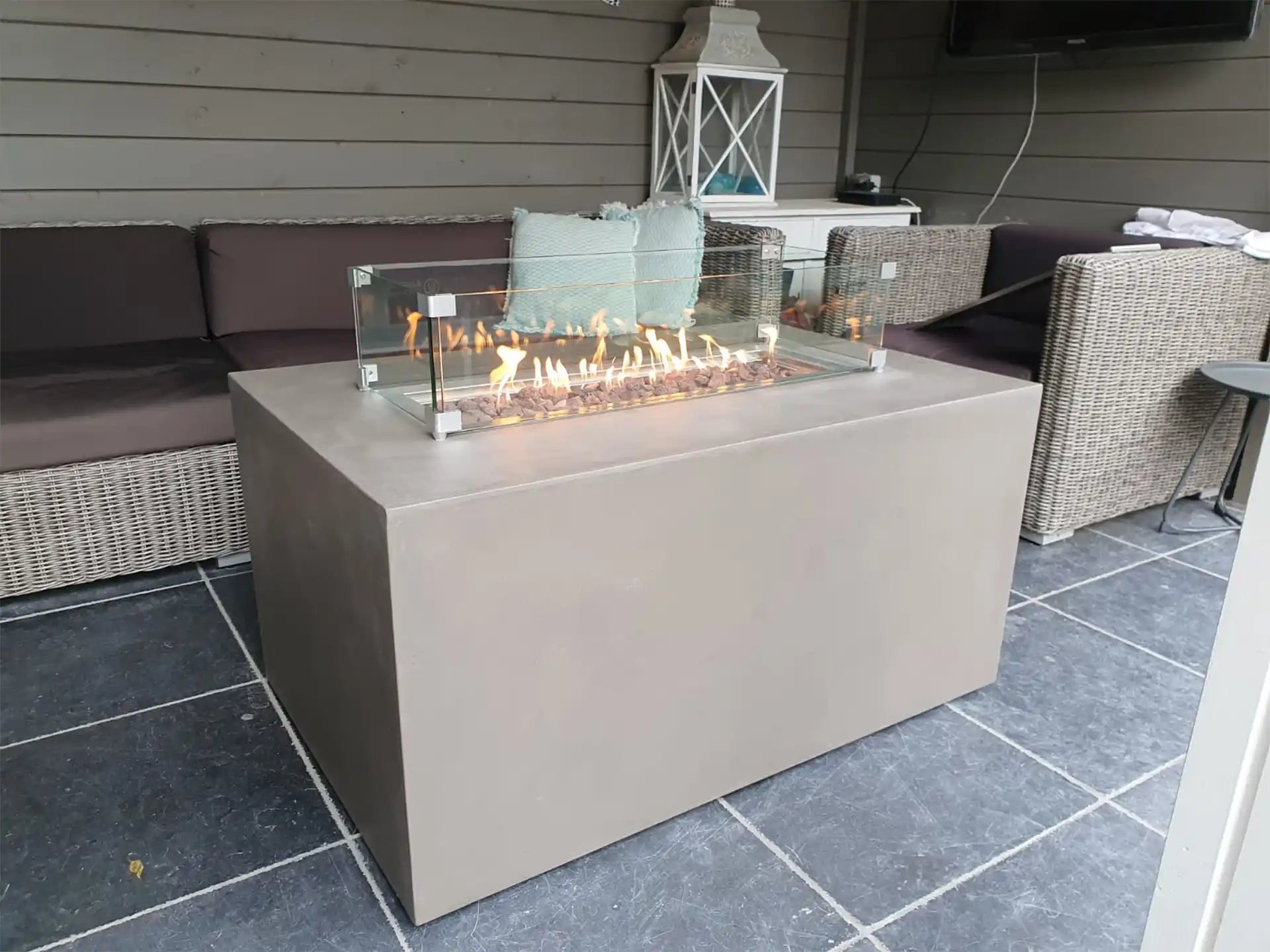 Gofire inbouwbrander 56 × 28 cm ingebouwd in moderne vuurtafel van betonlook, geplaatst op overdekt terras.
