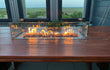 Gofire inbouwbrander 75 × 25 cm met glasombouw, geplaatst op houten tafel met panoramisch uitzicht, vlammen sfeervol brandend.