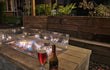  Gofire inbouwbrander 79 × 36 cm brandend in houten vuurtafel met glasombouw, sfeervol terras met drankjes en planten.