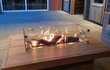 Gofire inbouwbrander 79 × 36 cm geplaatst in een strakke houten vuurtafel met vlammenspel op een terras in de avond.