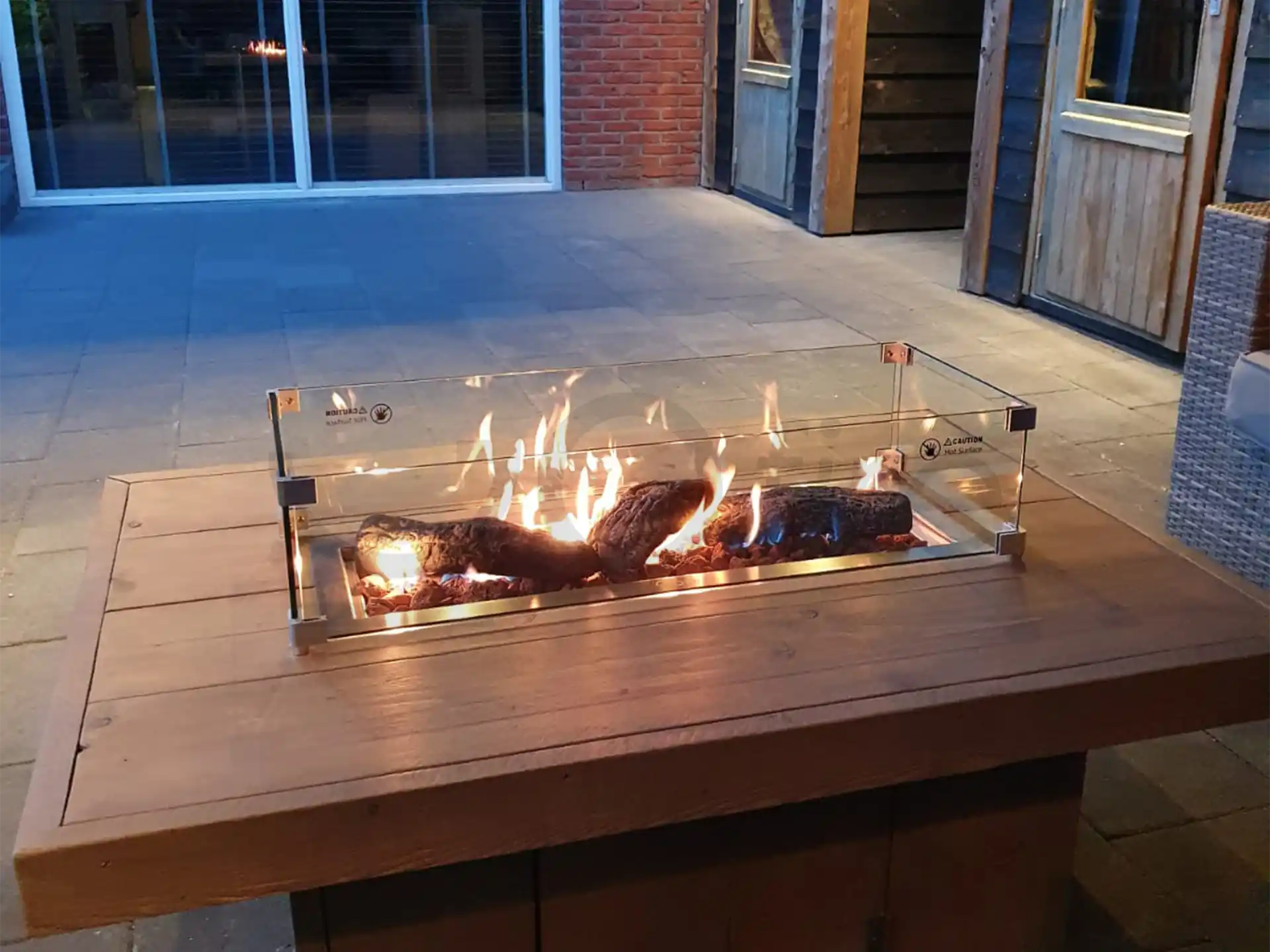 Gofire inbouwbrander 79 × 36 cm geplaatst in een strakke houten vuurtafel met vlammenspel op een terras in de avond.