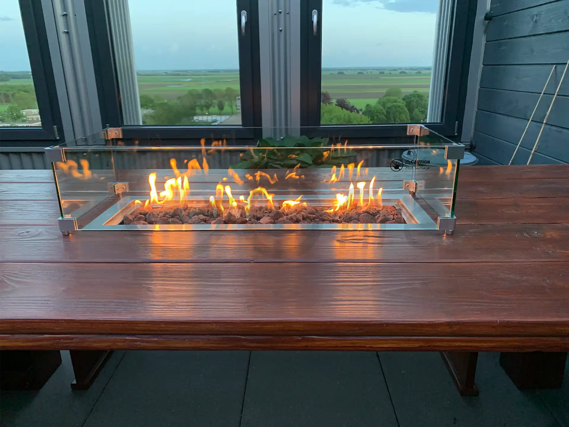 Gofire inbouwbrander 79 × 36 cm met glasombouw, geplaatst op houten tafel met panoramisch uitzicht, vlammen sfeervol brandend.