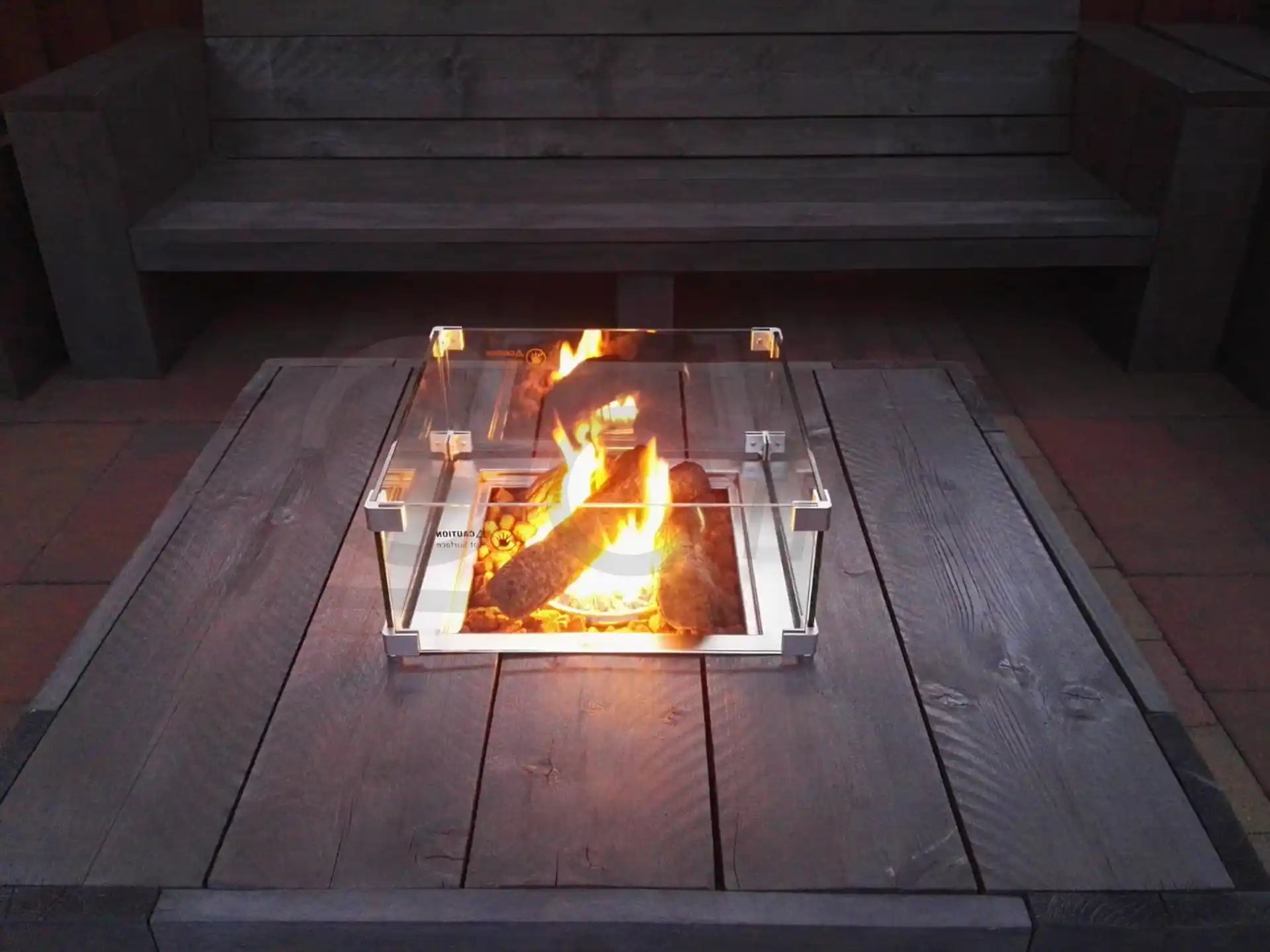 Gofire keramische stammetjes in een ingebouwde inbouwbrander, sfeervol brandend in een houten zitbank op het terras.