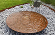 GoFire Soho waterschaal van cortenstaal met een diameter van 60 cm, geplaatst in een grindtuin met fonteintje en sierplanten.